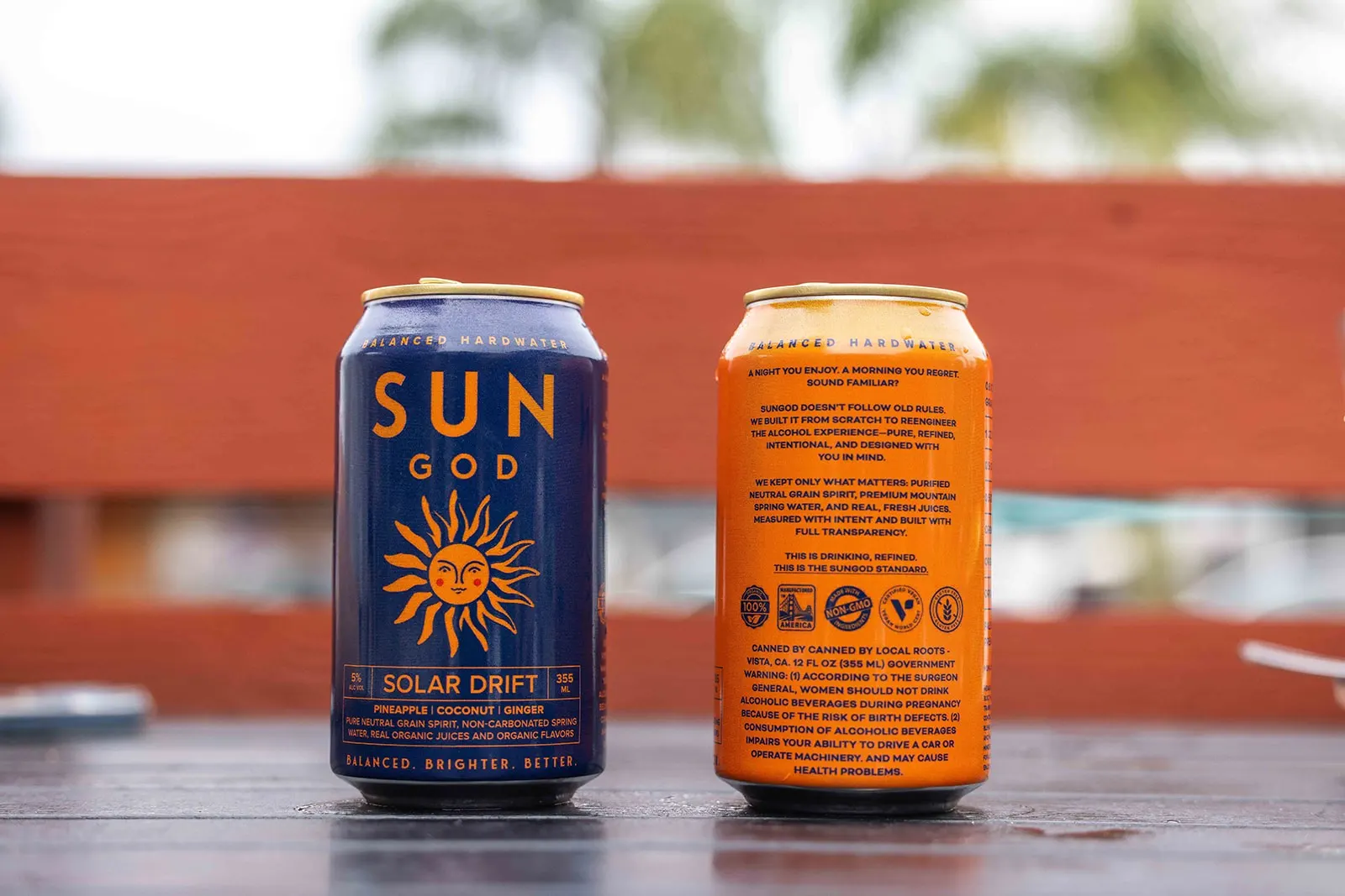 Cans of SUNGOD Solar Drift and Minted Sol side by side on a wooden surface