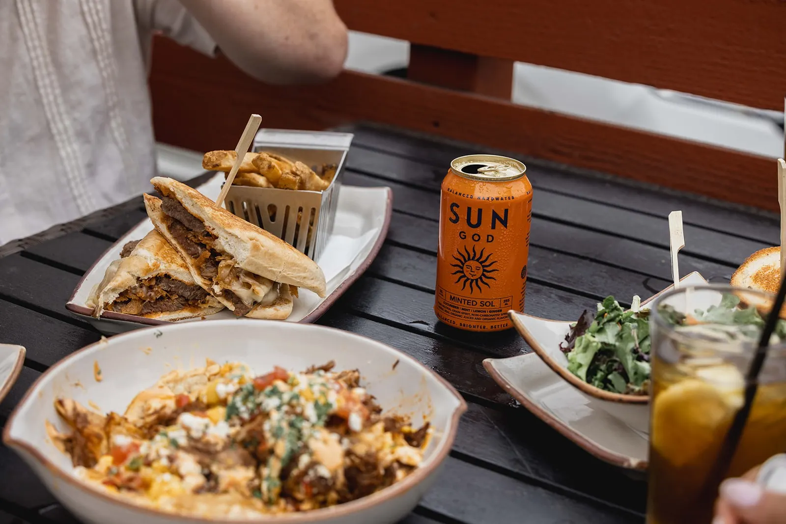 A can of SUNGOD on a picnic table spread with tacos and sides