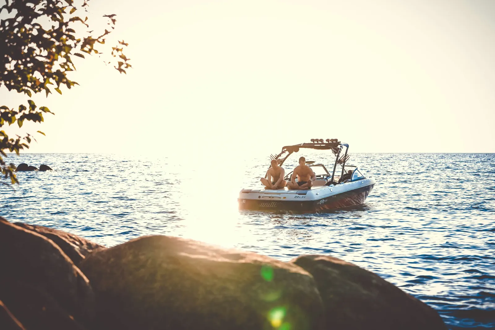 A small boat idling on calm water at sunset